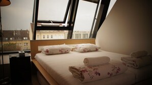 Ein Hotelzimmer mit Bett, Kissen und einem Fenster mit Blick auf Gebäude.