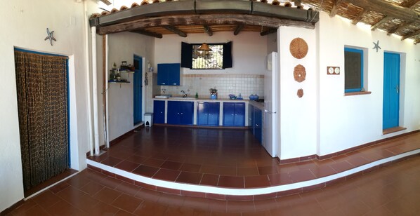 A kitchen with blue cabinets, a tiled backsplash, and a window with a hanging light fixture.