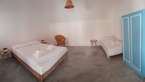 Een slaapkamer met een groot bed, een kleiner bed, een kledingkast, een stoel en een tafeltje.