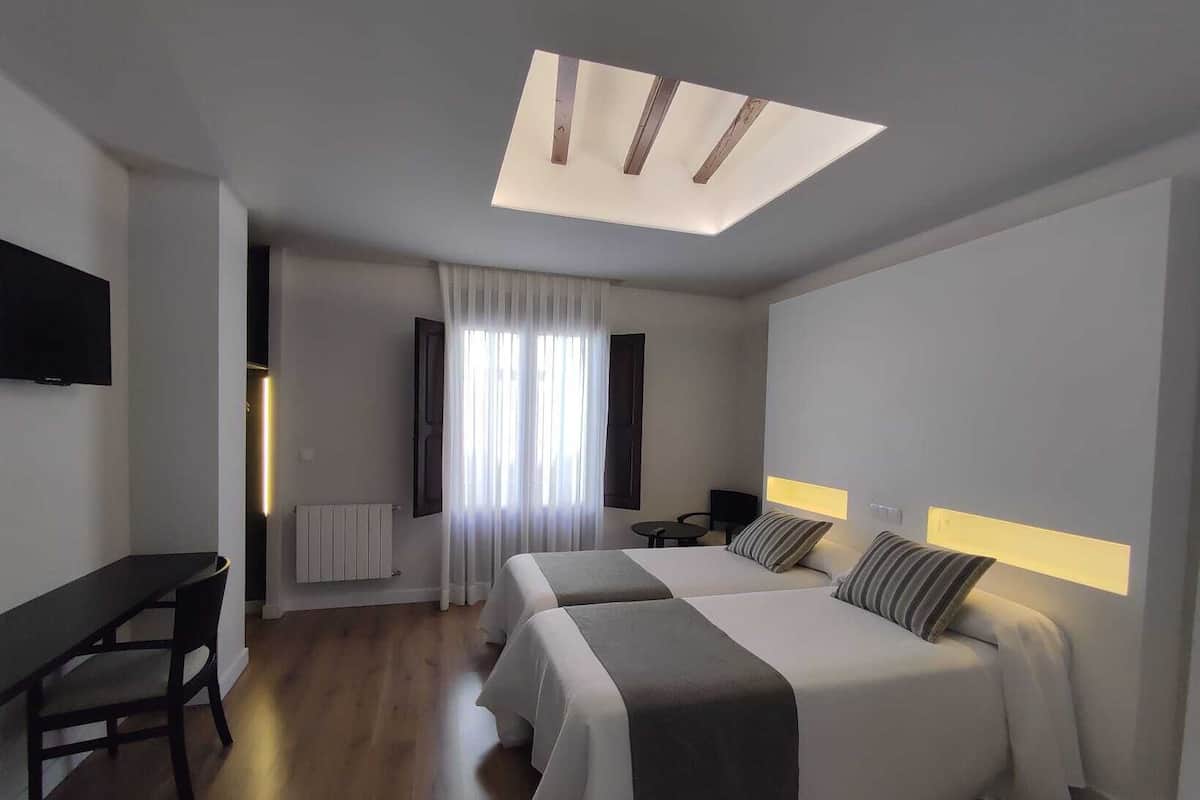 A modern hotel room with a large bed, a desk, and a TV.