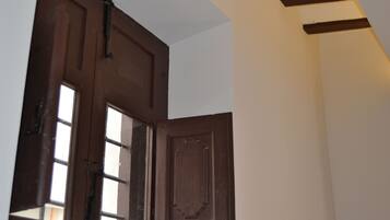 Una puerta de madera marrón con un ventanal, una pared blanca y una viga de madera en el techo.