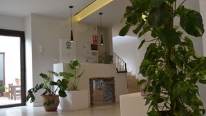 A modern living room with a staircase, potted plants, and a minimalist design. - Hotel La Vera Cruz (Caravaca de la Cruz)