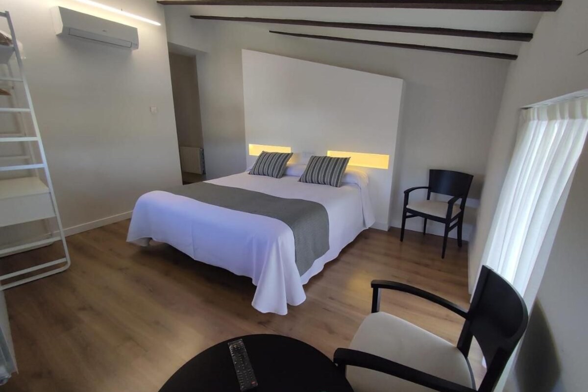 A hotel room with a bed, bedside tables, a chair, and a small table.