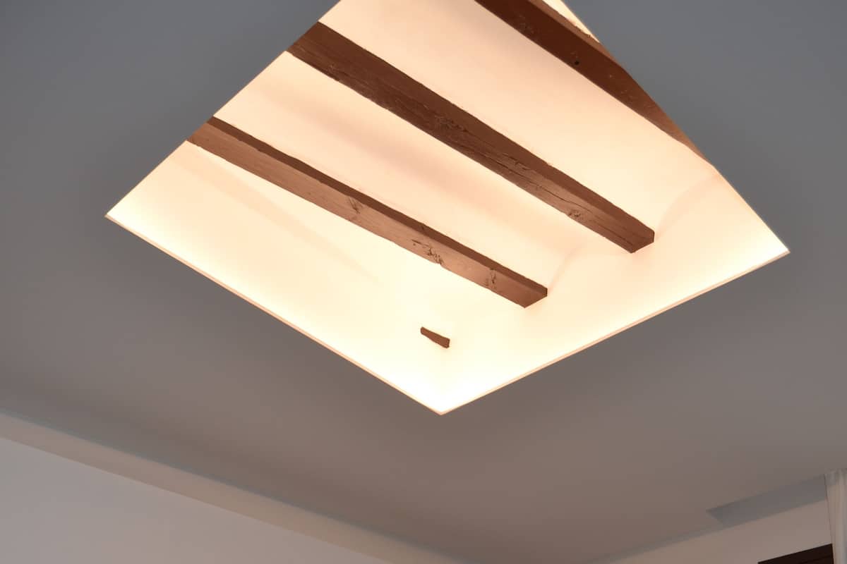 A hotel room with two beds, a ceiling light fixture, and a door.
