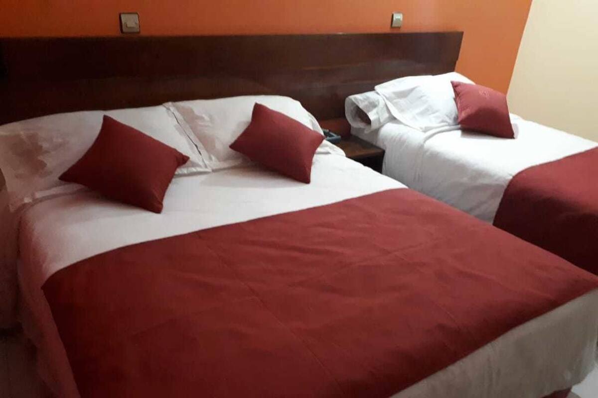 Une chambre d’hôtel avec deux lits, chacun étant équipé de draps rouges et blancs.