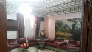 Een woonkamer met een zithoek, een ronde salontafel en een schilderij aan de muur.