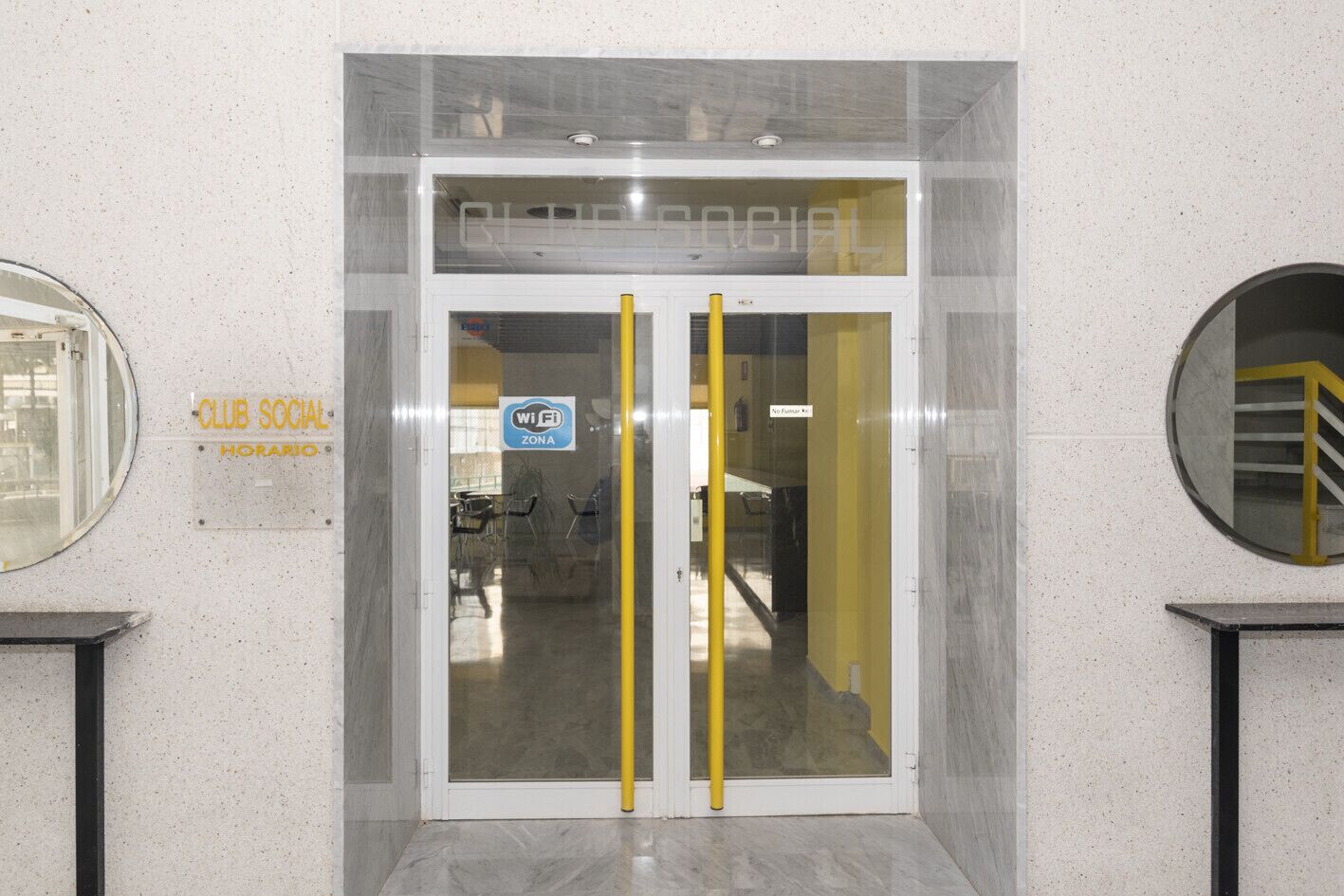 A Club Social entrance with a WiFi sign, a glass door, and a yellow handrail.