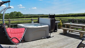 A hot tub on a wooden deck with a view of a grassy field and a wooden fence. - Rivendell Glamping Pod - UK11881 (Holsworthy, near Launceston)