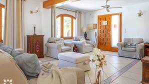 Un amplio salón con sofá, sillones, una mesa de centro y un jarrón decorativo.