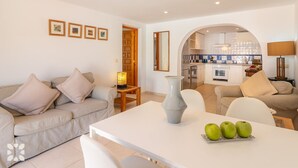 Una sala de estar moderna con un sofá, una mesa de comedor con manzanas y una cocina al fondo.