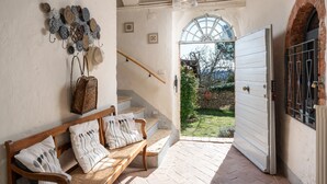 Ein gemütliches Interieur mit einer hölzernen Bank, einer Treppe und Blick auf den Garten durch eine geöffnete Tür.