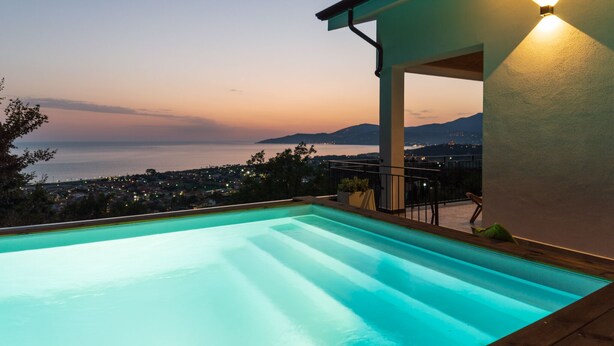 Ein Pool mit Blick auf eine Stadtlandschaft und Berge im Abenddämmerung.