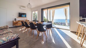 Ein modernes Wohnzimmer mit Essbereich, Fernseher und Balkon mit Blick.