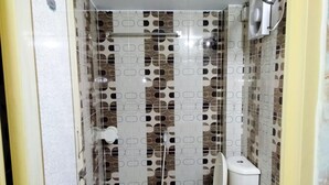 A small bathroom with a toilet, a sink, and a shower. - Hotel Charu (Barisal)