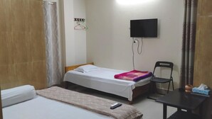 A hotel room with two beds, a TV, a desk, and a chair. - Hotel Charu (Barisal)
