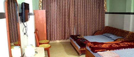 A hotel room with a bed, a desk with a chair, a mirror, a television, and a curtain.