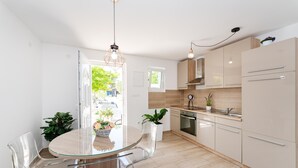 Una cocina moderna con una mesa de comedor de vidrio, sillas transparentes y armarios de madera clara.