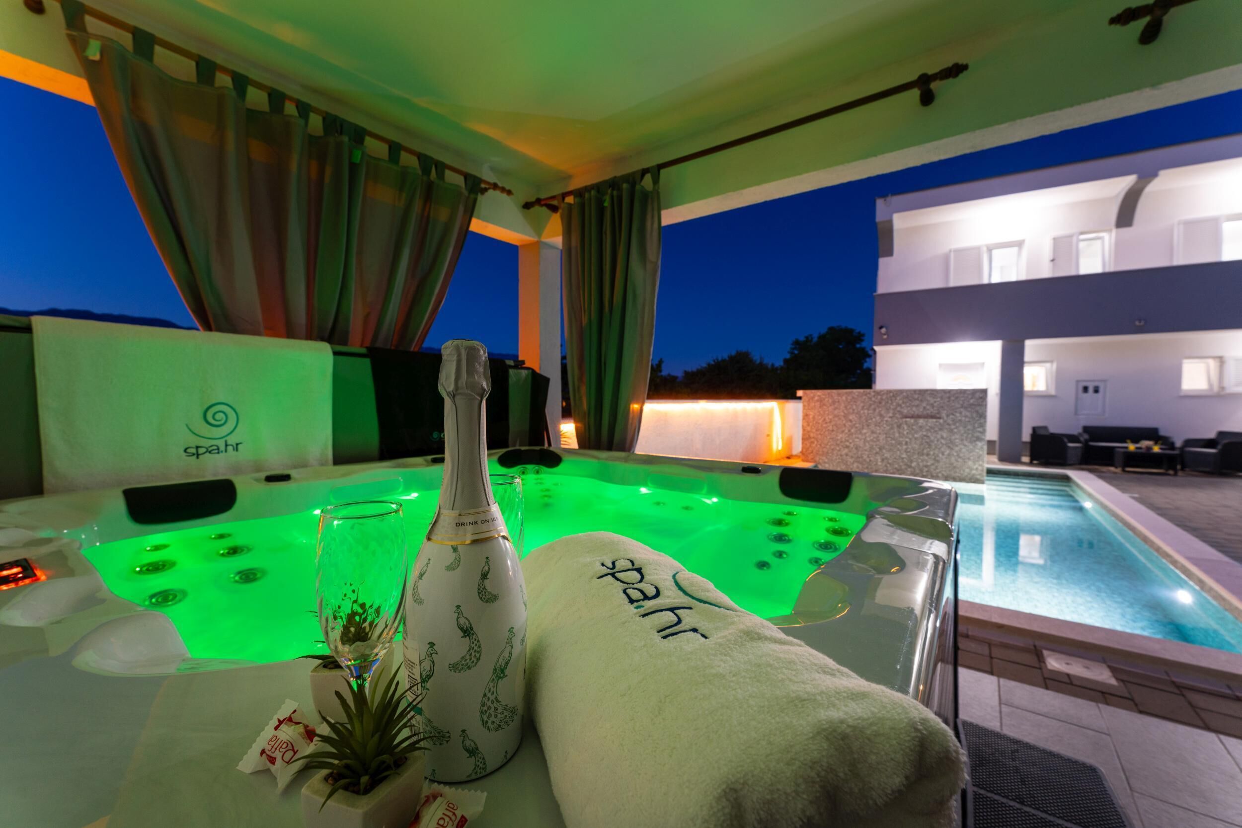 Een wellnessruimte met een bubbelbad, een fles en handdoeken.