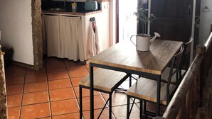 Une cuisine rustique avec une table et un banc en bois, un sol carrelé et un plafond en bois.