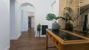 A hallway with wooden flooring, a large mirror with a palm leaf design, a wooden console table, and a potted plant. - ⭐ The Colosseum Mansion ⭐ (Roma)