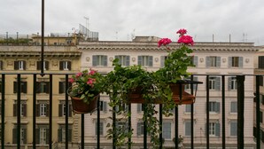 A balcony with potted plants and a view of a historic building with multiple windows and balconies. - ⭐ The Colosseum Mansion ⭐ (Roma)