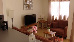 A modern living room with a flat-screen TV, a sofa, a coffee table, and a small side table.