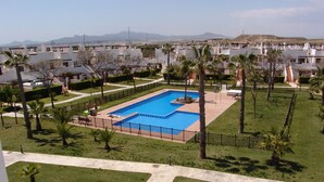 A residential area with a swimming pool surrounded by palm trees and a view of distant mountains.
