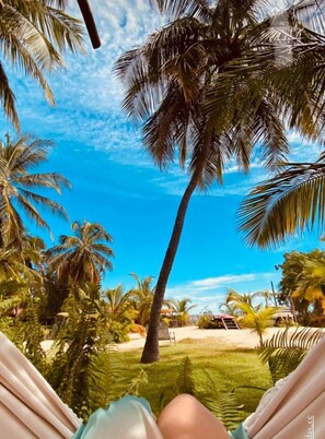 A hammock in a tropical setting with palm trees and a clear blue sky. - Casa das Rendas Exclusive Bungalows (Amontada)
