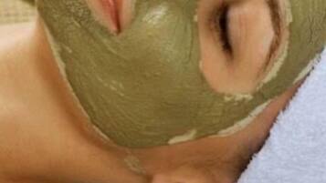 Una persona con máscara facial verde, acostada con una toalla.