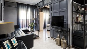 A modern living room with a sofa, a TV, and a glass coffee table. - Holi-Rent Gran Poder (Sevilla)