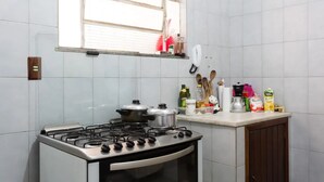 Een keuken met een gasfornuis, twee pannen, een koffiezetapparaat en diverse etenswaren op het aanrecht.