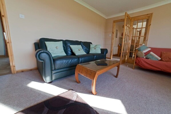 A living room with a dark blue sofa, a wooden coffee table, and a red sofa.