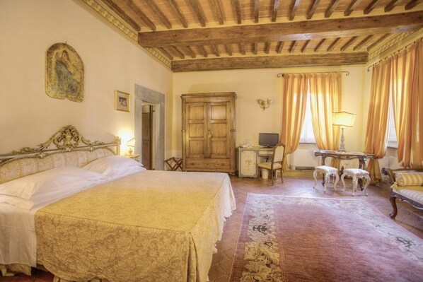 Una camera da letto con un letto grande, una scrivania in legno, una sedia e un tavolino con due sgabelli.