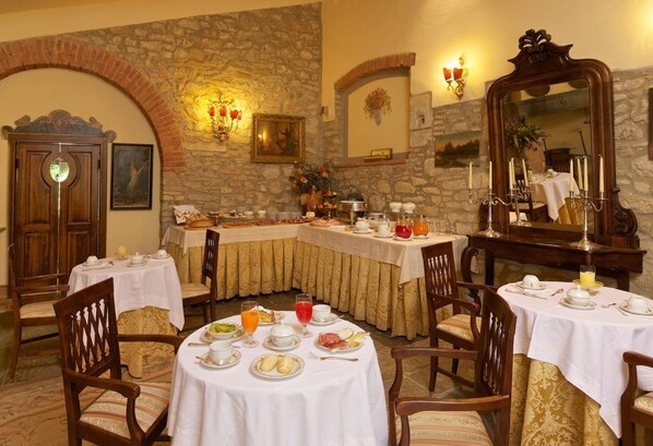 Comedor con mesas redondas, sillas y un fondo de pared de piedra.