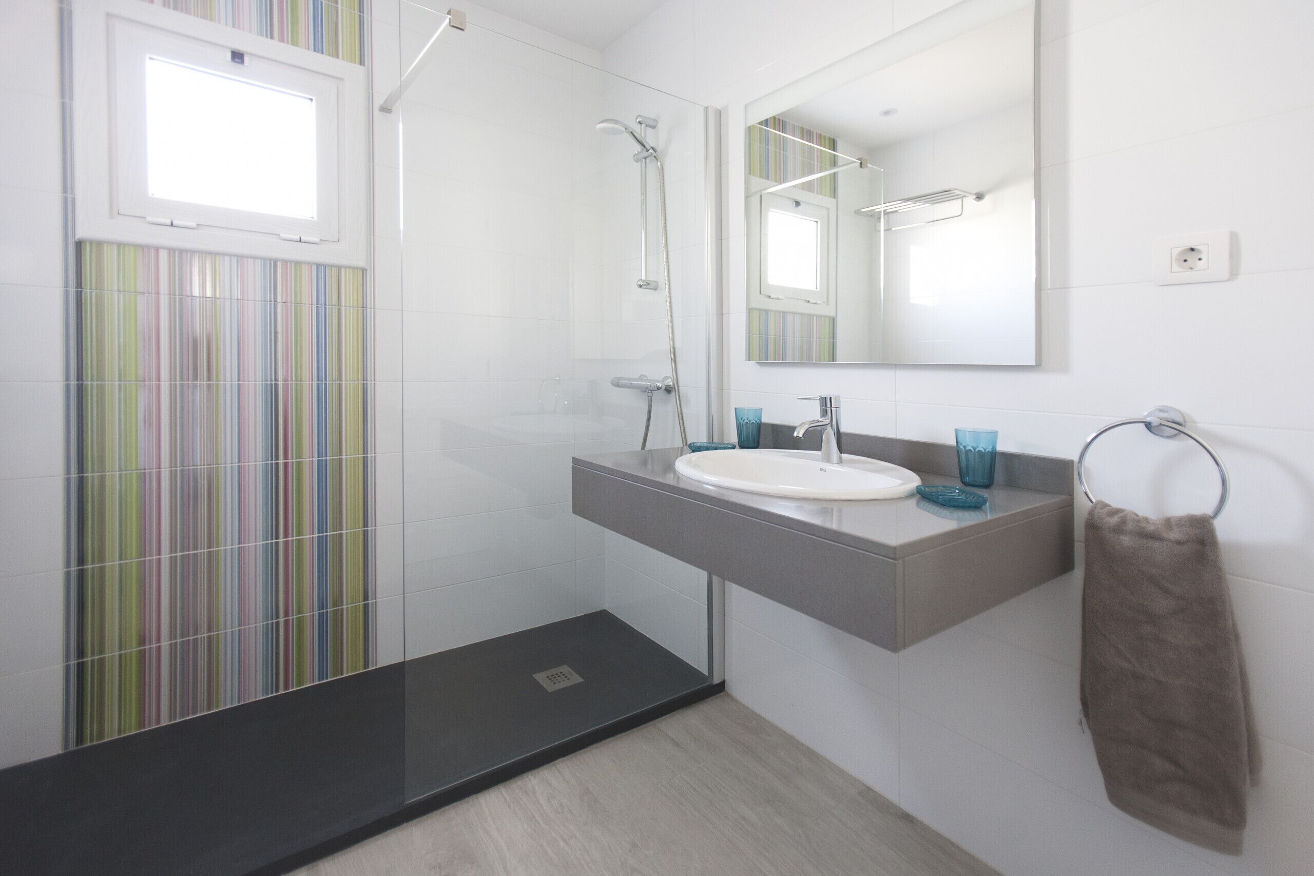 A modern bathroom with a shower, a sink, and a mirror.