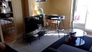 A living room with a TV, a coffee table, and a dining area with a table and chairs. - 70m2 apartment in the district of the barracks of Bonne (Grenoble)