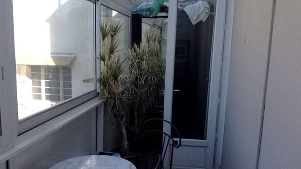 A small balcony with a white table and chairs, a potted plant, and a sliding door. - 70m2 apartment in the district of the barracks of Bonne (Grenoble)