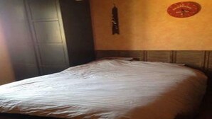 A room with a bed, a wooden headboard, a wall clock, and a dark door. - 70m2 apartment in the district of the barracks of Bonne (Grenoble)