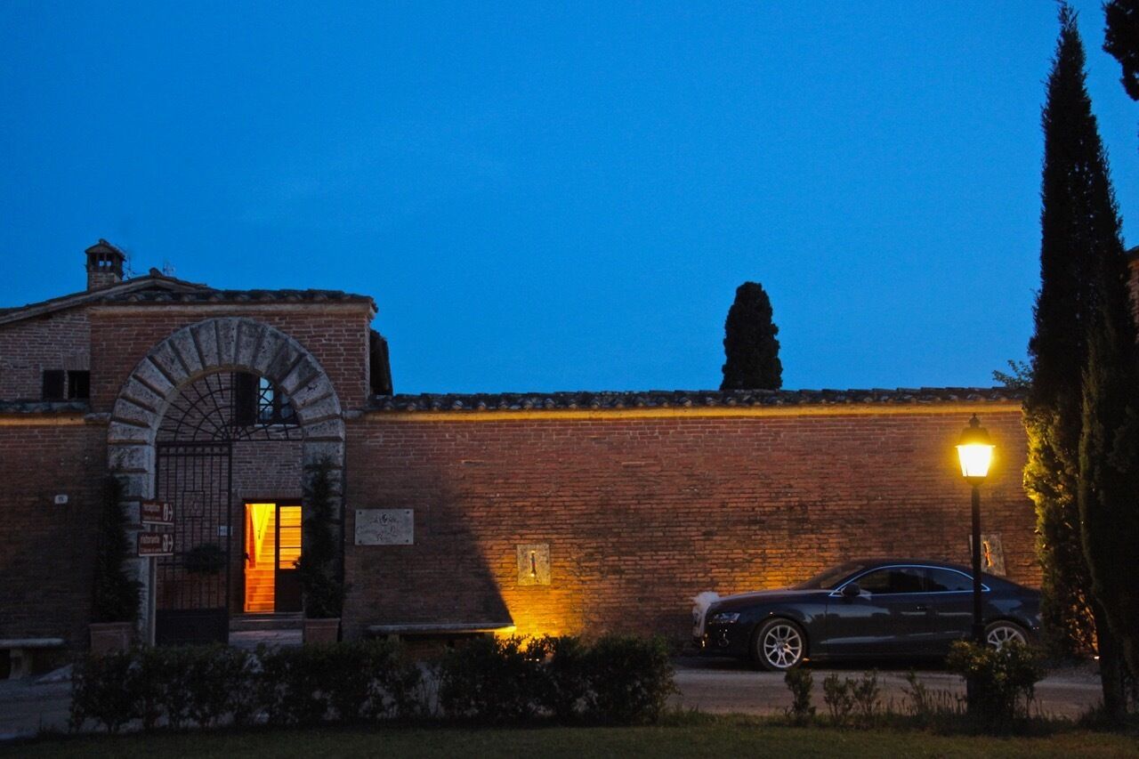 Un bâtiment en briques avec une grande entrée en arc de cercle et une voiture garée devant.
