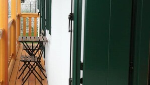 Un terrazzo in legno con mobili da esterno e una porta verde.