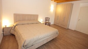Una camera da letto con un letto grande, un comodino, una sedia, un armadio e una porta.