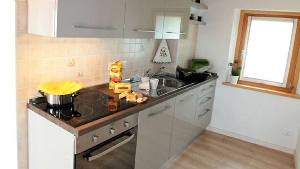 Una cucina moderna con travi in legno, un fornello e una finestra.