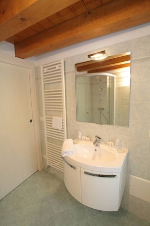 A bathroom with a white sink, a mirror, and a shower. - Casa Zoldan, Tublat (Polcenigo)