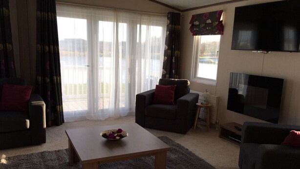 A living room with a sofa, armchair, coffee table, and a TV.