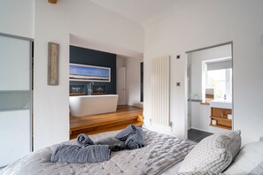 A bedroom with a bed, a view of the bathroom, and a painting on the wall. - Sybil Cottage (4), Holme-next-the-Sea, Norfolk (Holme-next-the-Sea)