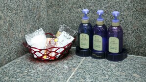 A granite countertop with a red basket containing toiletries and three bottles of hair and body care products. - HOTEL D-WAVE Shinjuku - Adults Only (Tokyo)
