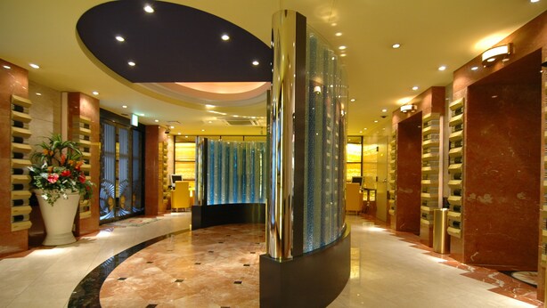 A hotel lobby with a curved marble floor, a central column, and a decorative fountain. - HOTEL D-WAVE Shinjuku - Adults Only (Tokyo)