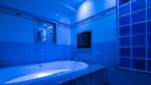 A modern bathroom with a freestanding bathtub, a window, and a built-in sink. - HOTEL D-WAVE Shinjuku - Adults Only (Tokyo)