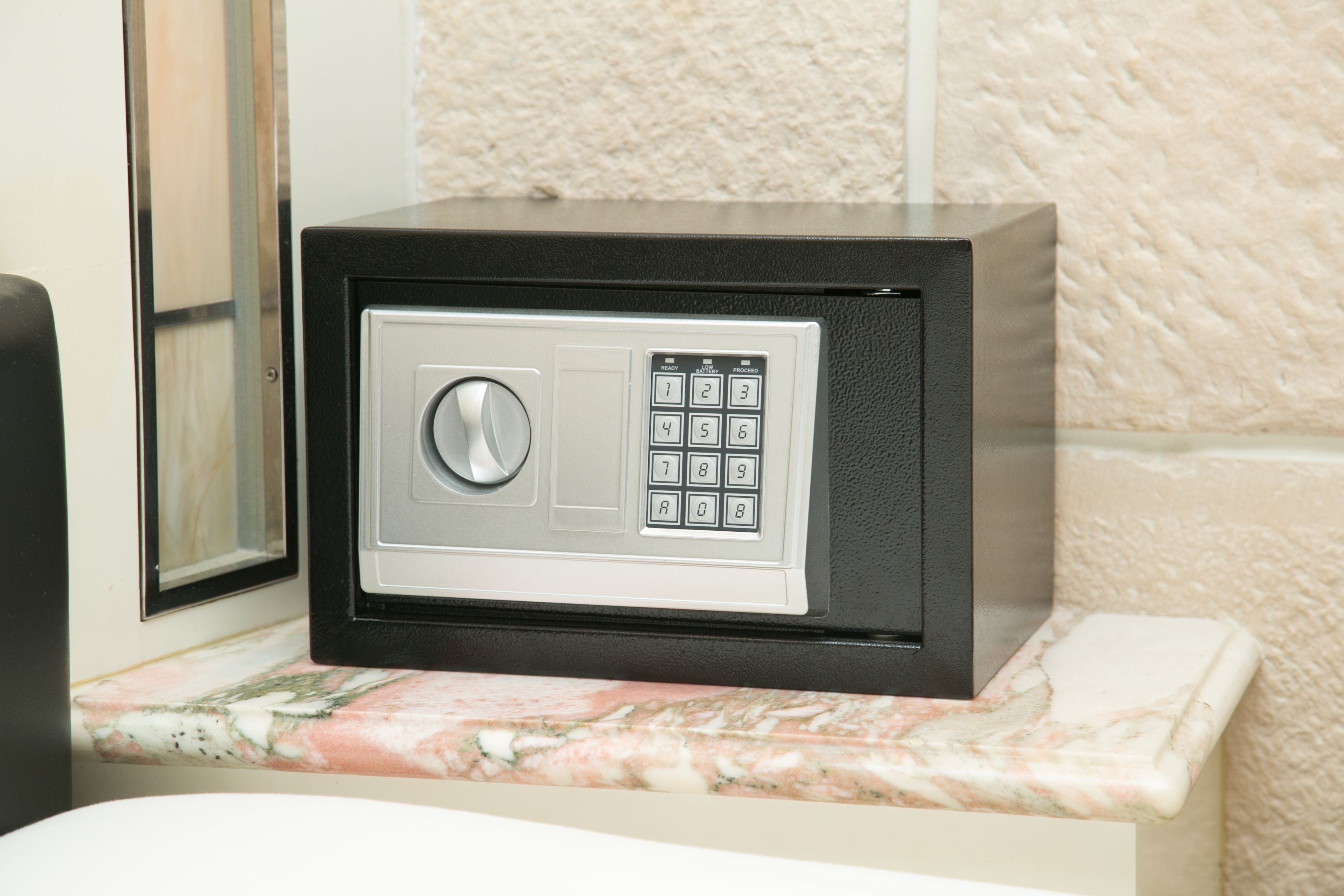 A safe with a keypad and a combination lock on a marble countertop.
