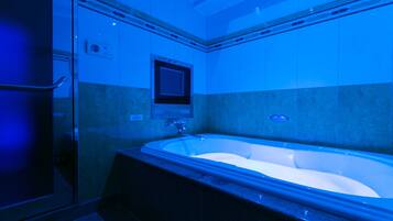 A modern bathroom with a freestanding bathtub, a glass shower enclosure, and a wall-mounted control panel.